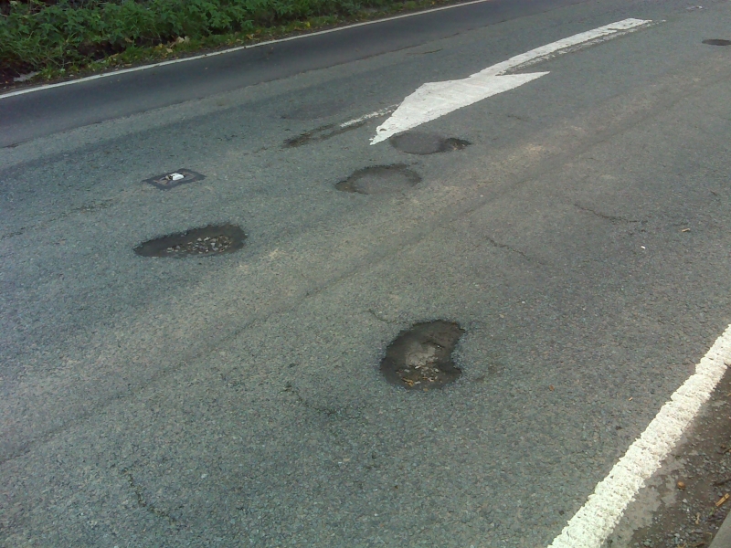 Damage to surface of A51 on southbound lane north of Boar's Head